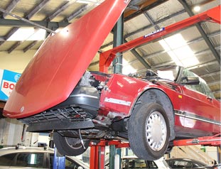 Red car on a car lift in service centre