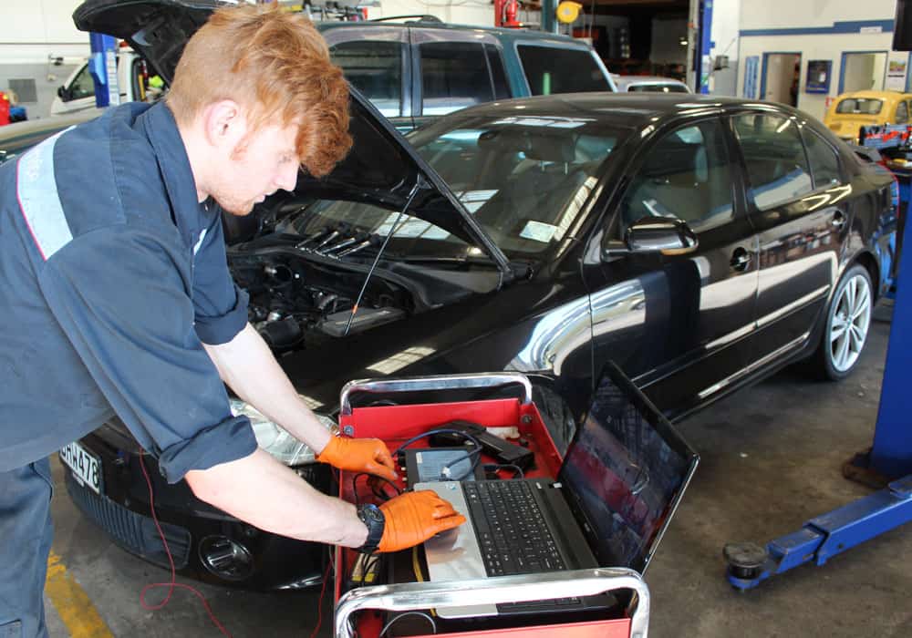 Diagnostic tools being used by a young mechanic during an affordable auto service