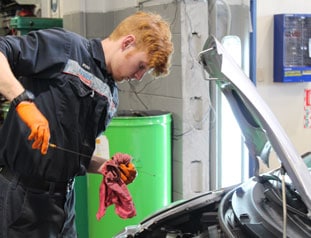 Young mechanic performing an oil check